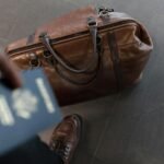 Brown leather bag with passport in an airport setting, ideal for travel and fashion themes.