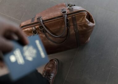 Brown leather bag with passport in an airport setting, ideal for travel and fashion themes.