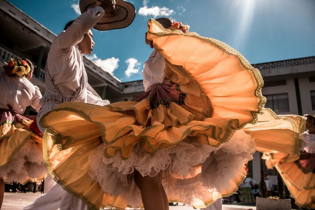 Energetic dancers in colorful traditional attire performing outdoors under the bright sun.