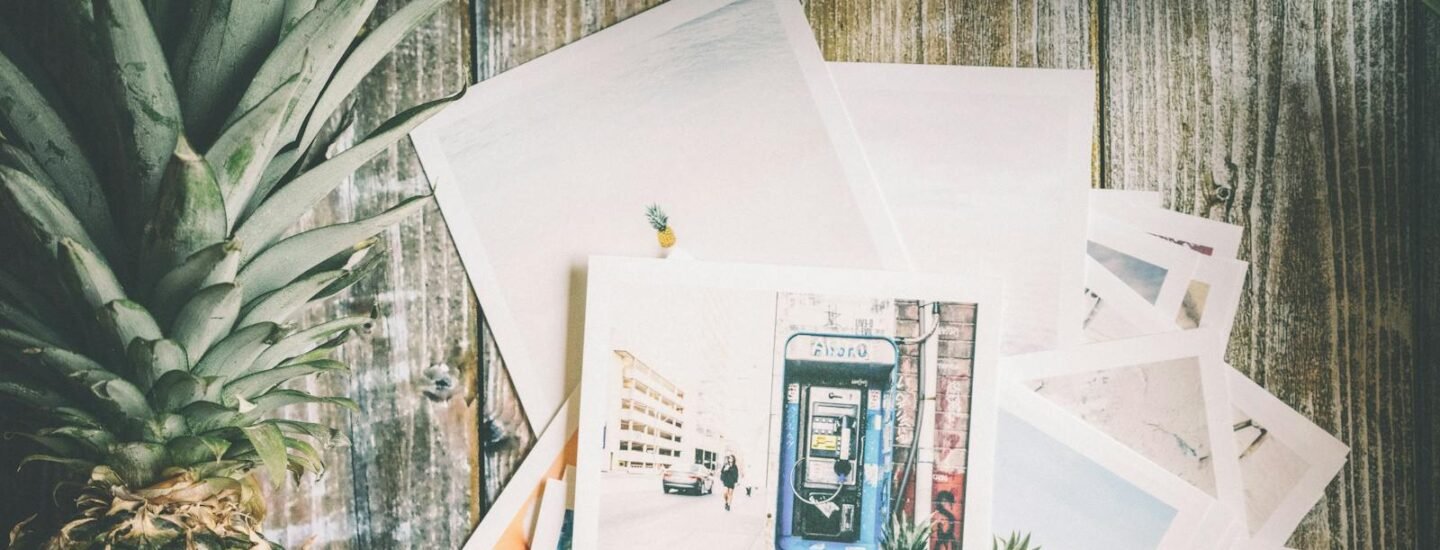 An artistic collection of travel-themed photos with a pineapple on rustic wood.