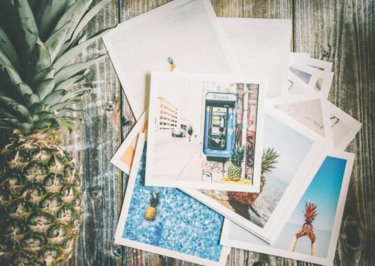 An artistic collection of travel-themed photos with a pineapple on rustic wood.