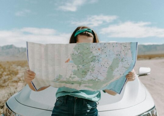 A woman holds a map while traveling through the scenic desert of California, USA.