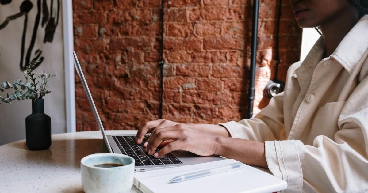 Woman working on a laptop with coffee in a cozy café, highlighting a productive and modern vibe.