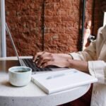 Woman working on a laptop with coffee in a cozy café, highlighting a productive and modern vibe.