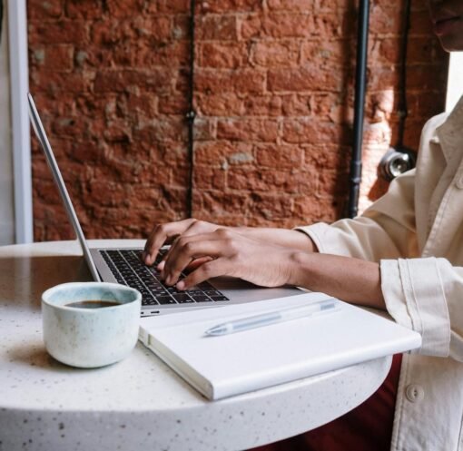 Woman working on a laptop with coffee in a cozy café, highlighting a productive and modern vibe.