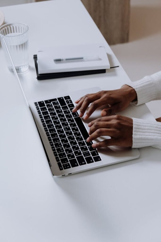 A woman typing on a laptop at a modern home office desk indoors.