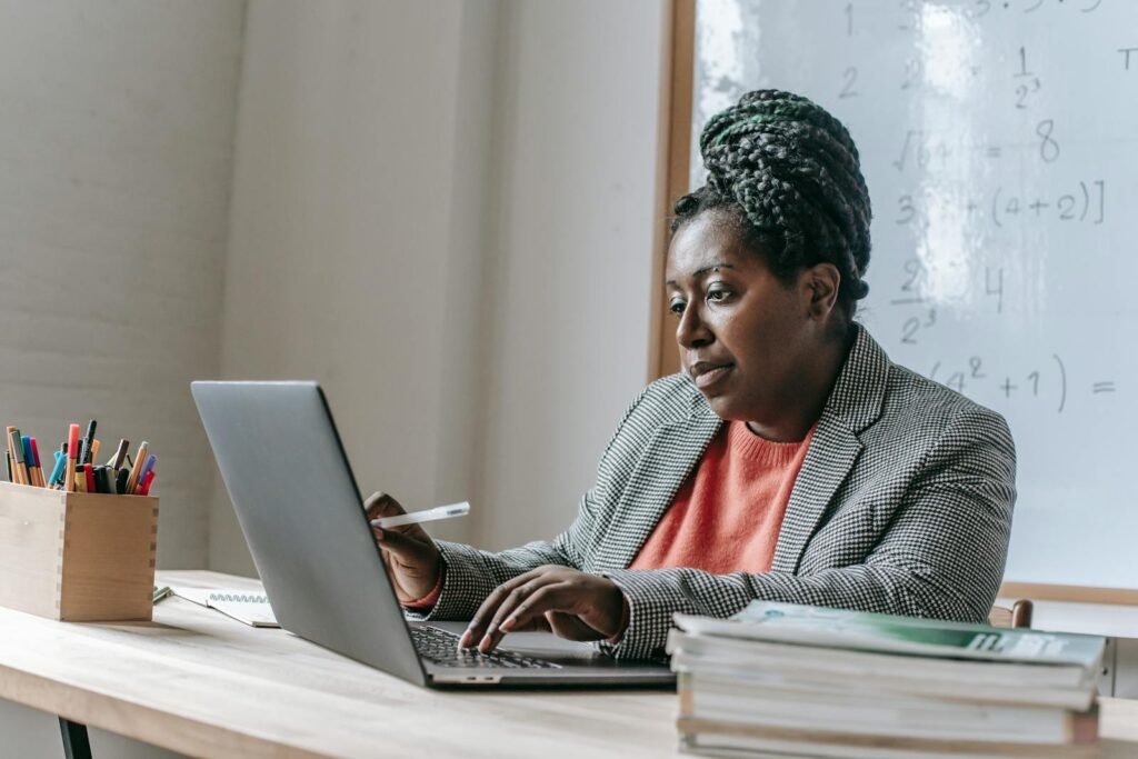 Professional African American woman concentrating on laptop work in an educational setting.