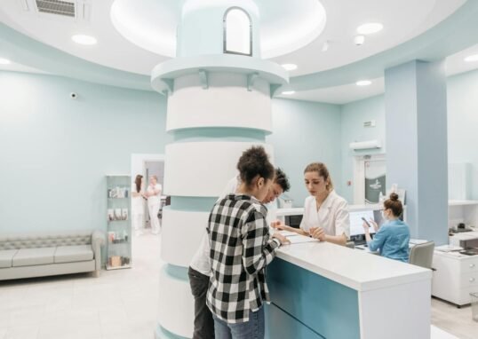 Bright, welcoming clinic reception with patients interacting with staff for registration.