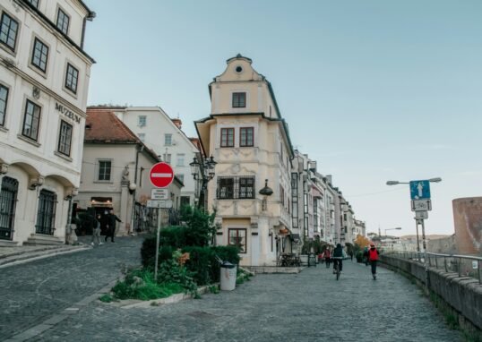 people walking down a cobblestone street in a european city