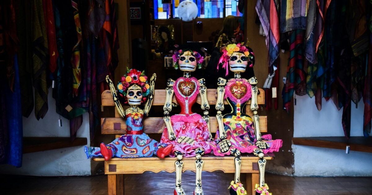 three Frida Kahlo skeleton dolls sitting on bench